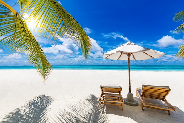 Perfekter tropischer Strand Sommerlandschaft mit Stühlen und Sonnenschirm auf weißem Sand in der Nähe des blauen Meereshimmels