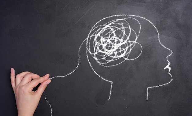 Perfil de una cabeza humana con una espiral enredada en el área del cerebro La cabeza está dibujada con tiza blanca Concepto de salud mental