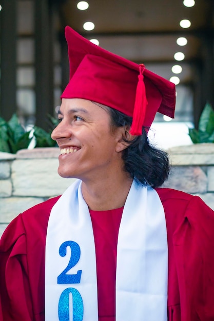 Perfil de jovem latino sorrindo em vestido vermelho de formatura