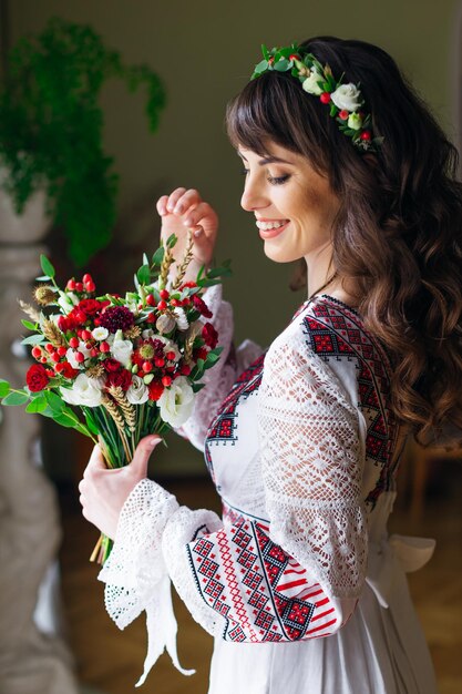 Perfil de noiva em um lindo vestido bordado com um buquê chique e uma coroa de flores na cabeça