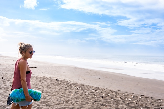 Perfil de uma jovem em uma praia olhando para o horizonte