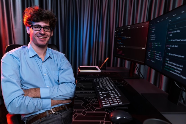 Foto perfil de un desarrollador de ti sonriente sentado frente a la información de desarrollo de software en la pantalla mirando a la cámara rodeado de la creación de codificación de programas para la última versión de la aplicación en el sitio web gusher