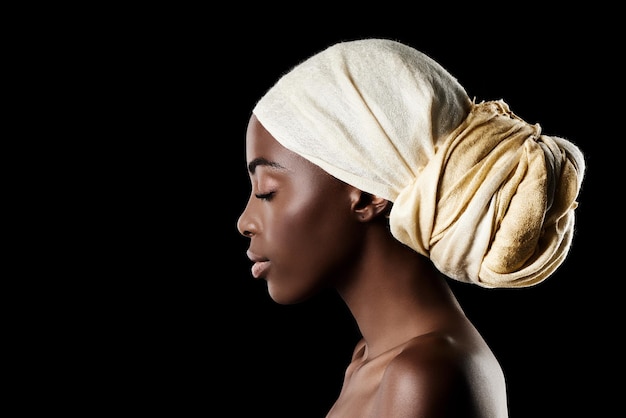 El perfil de la foto de estudio de belleza de una mujer hermosa que lleva un pañuelo en la cabeza contra un fondo negro