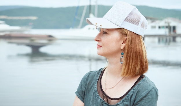 Perfil de una hermosa mujer madura con una gorra disfrutando de la vista al mar en verano