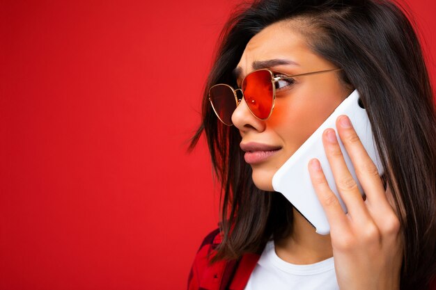 Perfil lateral foto en primer plano de atractiva mujer morena joven triste vistiendo elegante camisa roja blanca