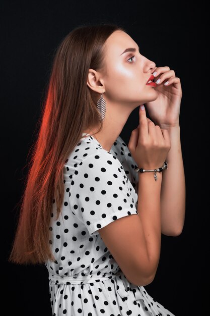 Perfil de muchacha hermosa con el pelo largo contra negro.