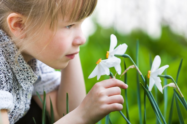 Perfil del narciso blanco que huele al aire libre de la muchacha bastante pensativa linda del niño en día soleado de verano o de primavera.