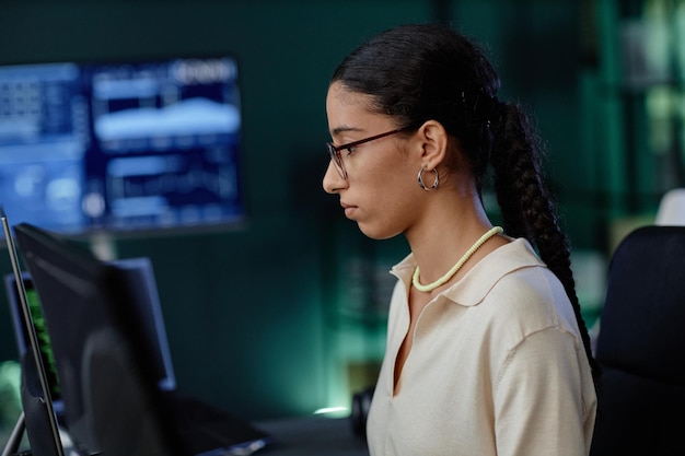 Perfil de una programadora de Oriente Medio con pendientes elegantes usando computadora en el lugar de trabajo