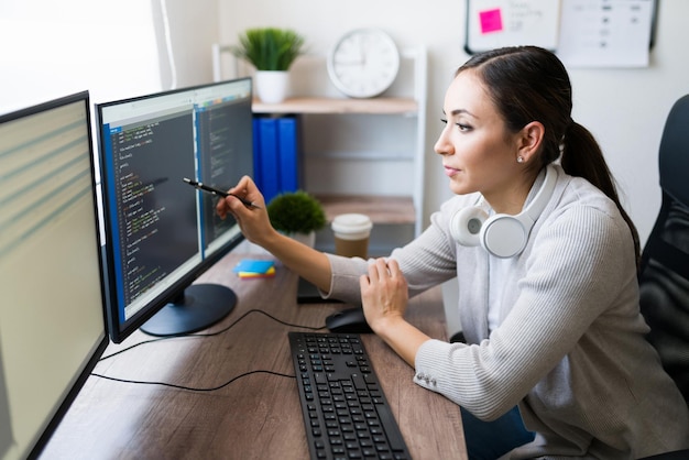 Foto perfil de una programadora profesional revisando el software de codificación de una aplicación en su computadora en casa