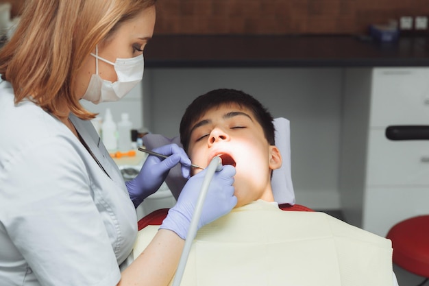 Perforación de dientes y succión de saliva con un dentista eyector trata los dientes del paciente en un consultorio dental moderno