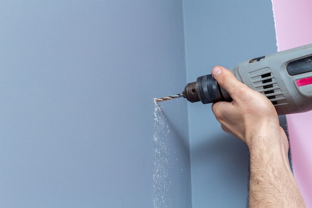 Perforar una pared gris con un taladro