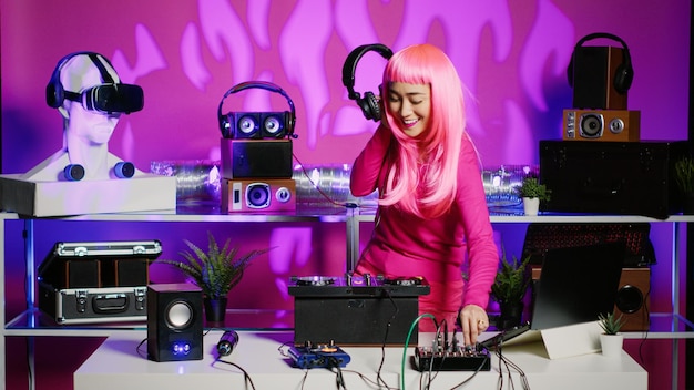 Performer, der am dj-tisch steht und techno-sounds mit einem professionellen mixer mischt und während des nachtclubkonzerts musik spielt. Asiatischer Künstler hört Audio, während er Remix im Studio spielt