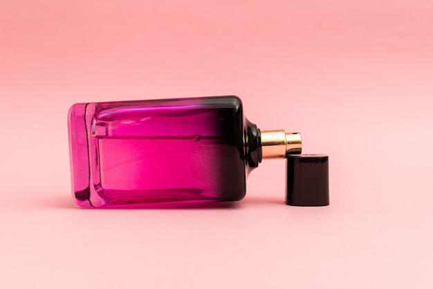 Perfume en una botella rosa sobre un fondo rosa