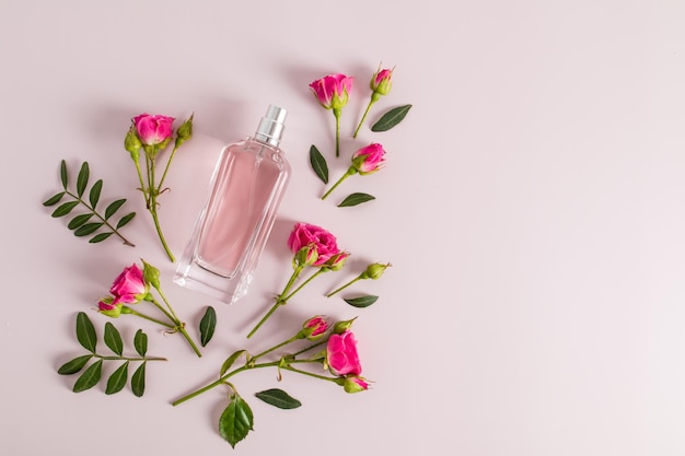 Perfume en una botella de vidrio sobre un fondo rosa con capullos de rosas frescas vista superior una copia del espacio Diseño de plantilla