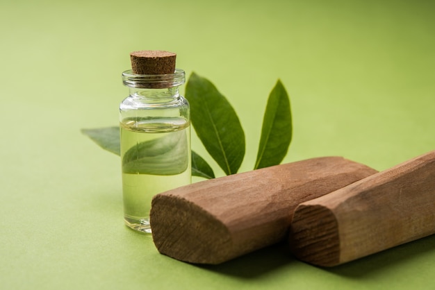 Perfume de chandan ou sândalo ou óleo com palitos, argamassa tradicional, em frasco miniatura e folhas verdes. foco seletivo