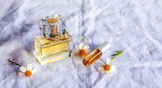 Perfume dourado e pequenos frascos de perfume com uma flor branca sobre fundo branco