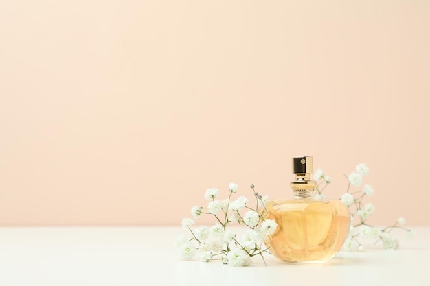 Perfume e flores contra fundo bege, espaço para texto