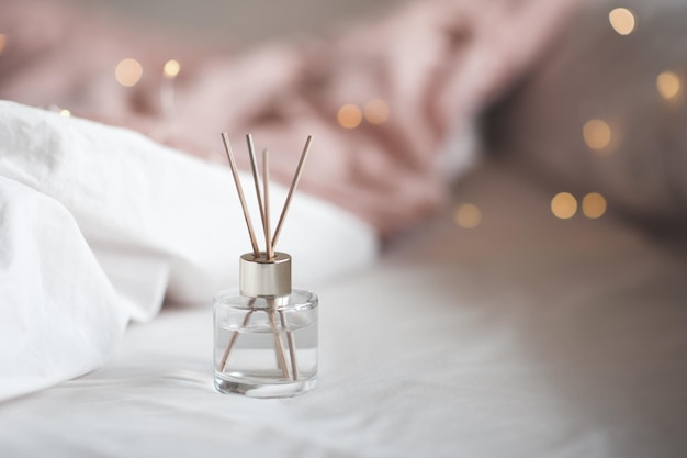 Foto perfume líquido casero en botella de vidrio con palos de bambú sobre luces brillantes cerca de la aromaterapia