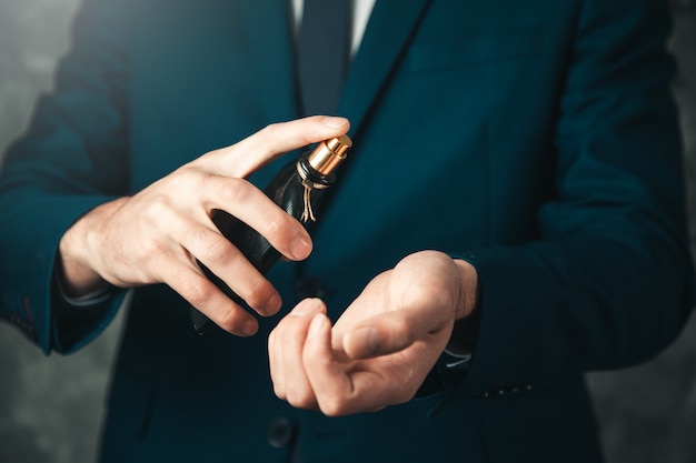 Foto perfume de mano de hombre sobre fondo oscuro