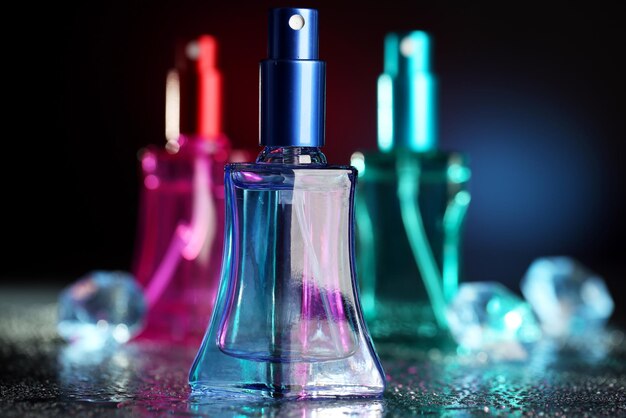 Perfume de mujer en hermosas botellas sobre fondo oscuro con luz de color