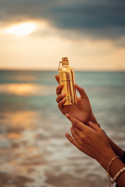 Perfume de mujer en la mano de la mujer contra el mar