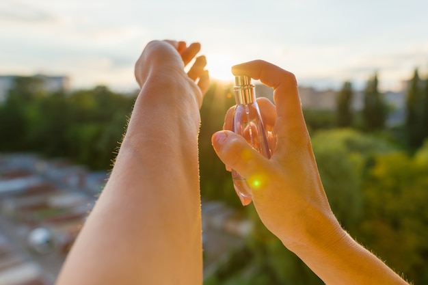 Foto perfume nas mãos, pôr do sol de noite