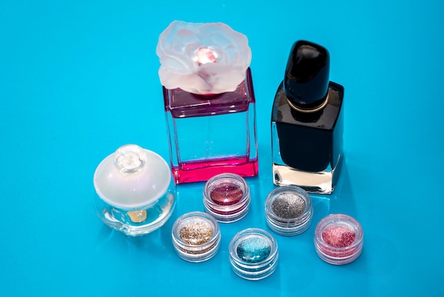 Perfumes femininos e brilhos de unhas isolados no azul