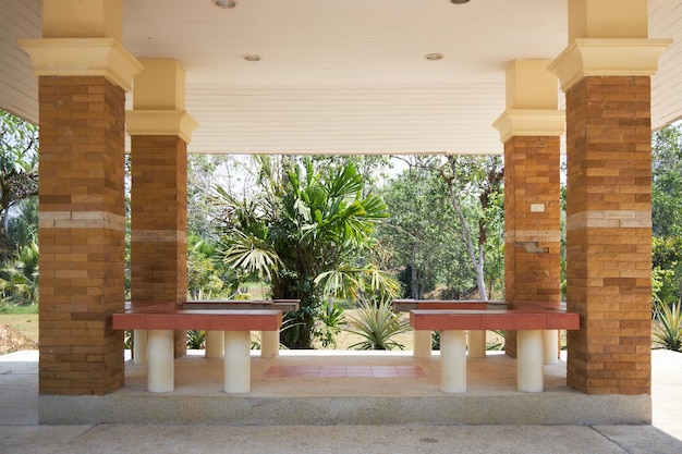 Pérgola cuadrada con bancos y cuatro columnas al mediodía.