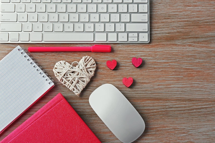 Foto periféricos de computadora con bolígrafo de corazones y cuadernos en mesa de madera