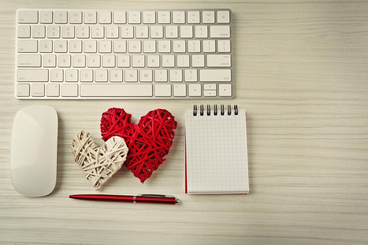 Foto periféricos de computadora con bolígrafo de corazones de mimbre y cuaderno sobre mesa de madera clara