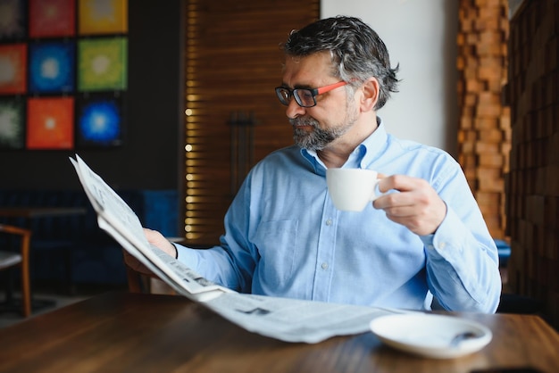 Periódico en la mañana Empresario senior en su oficina montando periódicos