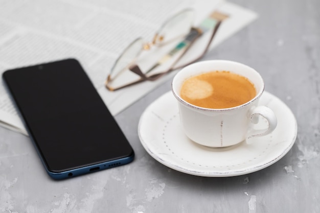 Periódicos y taza de café con gafas de lectura.