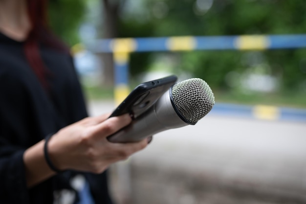 Periodista en una conferencia de prensa grabando notas con micrófono y dictafono de piojos smarthopne
