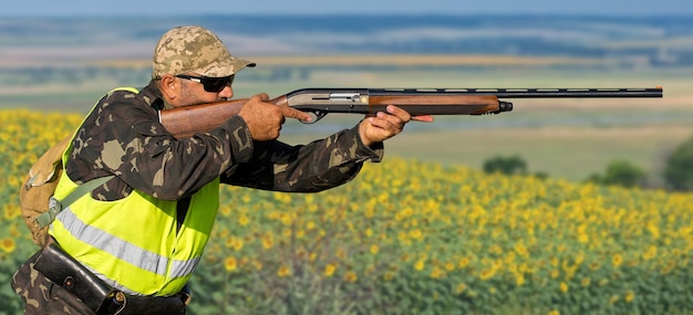 Foto período de caza temporada de otoño abierta un cazador con un arma en sus manos en ropa de caza en el bosque de otoño en busca de un trofeo un hombre está parado con armas y perros de caza rastreando el juegox9xa