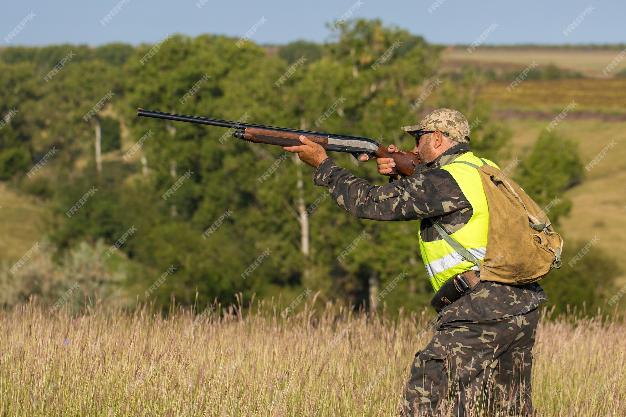 Periodo de caza, temporada de otoño abierta. un cazador con una pistola en  sus manos con ropa de caza en el bosque de otoño en busca de un trofeo. un  hombre está de pie con armas y perros de caza rastreando el juego.