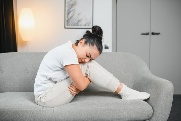 Período de menstruación día del ciclo de la mujer joven mensual mano femenina en dolor de estómago sufre de PMS premenstrual dolor de vientre o abdomen en la cama en casa Problema de salud Inflamación en el cuerpo