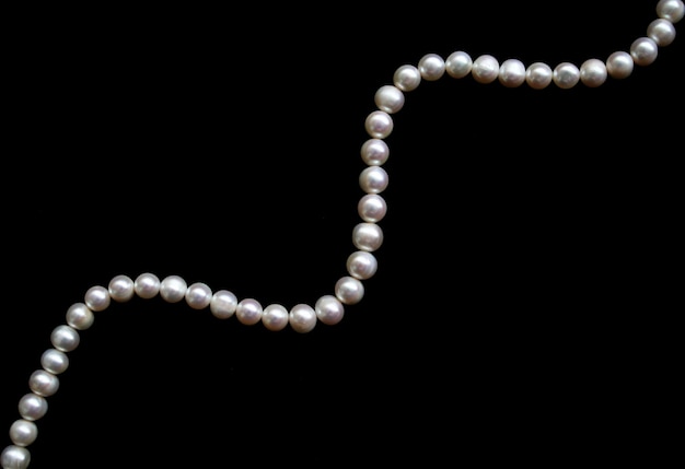 Perlas blancas sobre la seda negra como fondo.