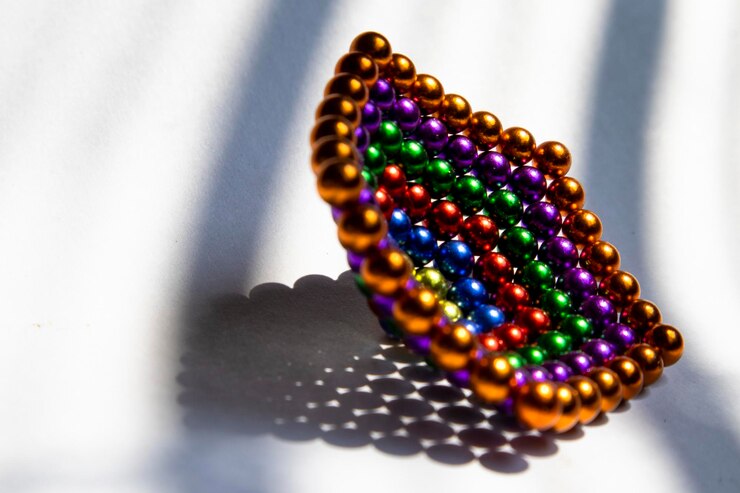 Foto perlas de colores con forma de pirámide en base blanca con iluminación de sombra a rayas