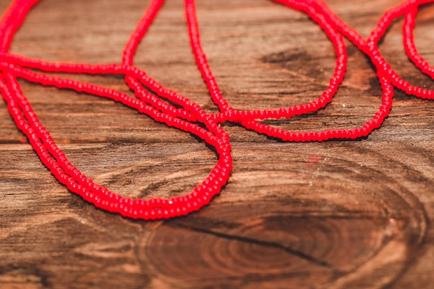 Perlas rojas sobre un fondo de madera. Cuentas y artesanías para la creatividad.