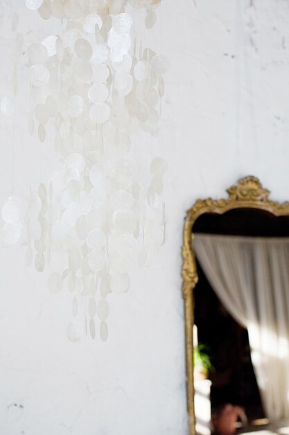 Perlmutt-Kronleuchter aus weißer Schale und goldener Vintage-Spiegel in hellem böhmischem Interieur