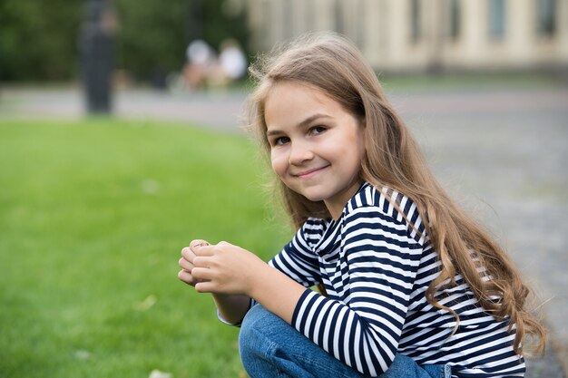 Permite que su hijo se cuide mejor Niño feliz sentado en cuclillas al aire libre Niña pequeña