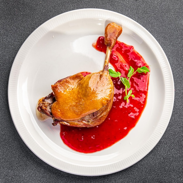 perna de carne confitada de pato, lanche de comida de refeição de molho de frutas vermelhas na mesa copie o fundo de comida do espaço