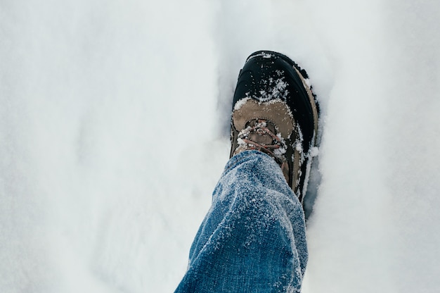 Perna masculina em um sapato, andando na neve