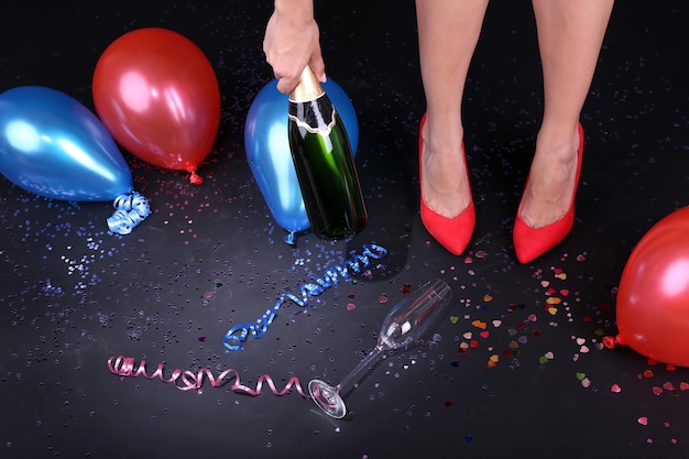 Pernas com champanhe de confete e balões no chão