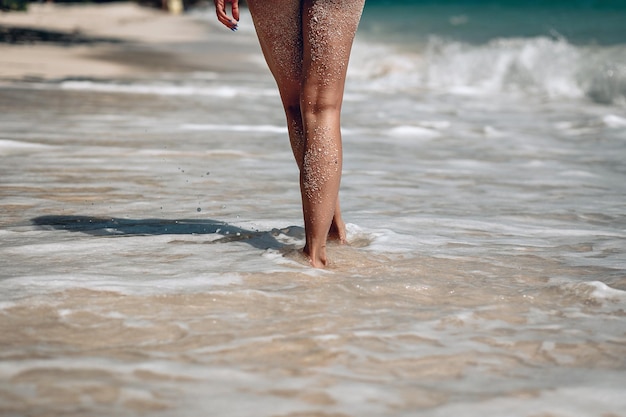 pernas da menina no contexto da água na praia Relaxando na praia