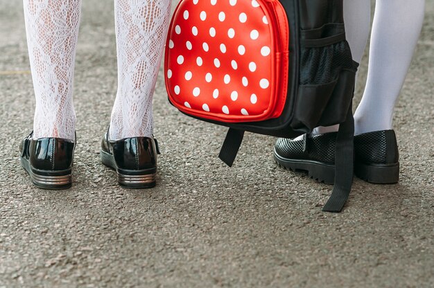 Pernas das meninas em uniforme escolar com uma mochila