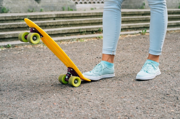 Pernas das mulheres em jeans e tênis ao lado de skate