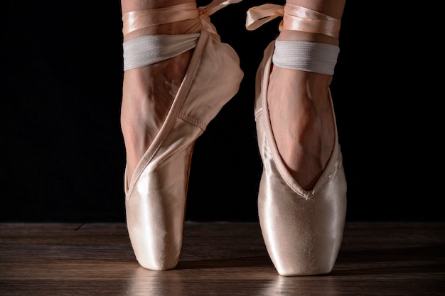 Foto pernas de bailarina clássica close-up em pointes no preto