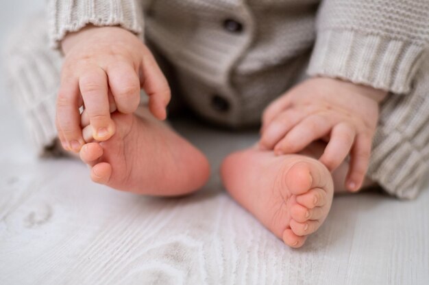 Pernas de bebê saudáveis, pés e dedos fechados em um terno de malha de cama