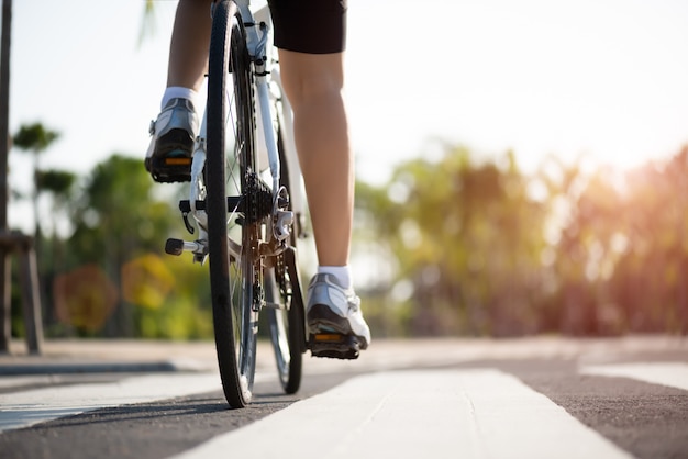 Pernas de ciclista mulher atleta andando de bicicleta de montanha na estrada de manhã.